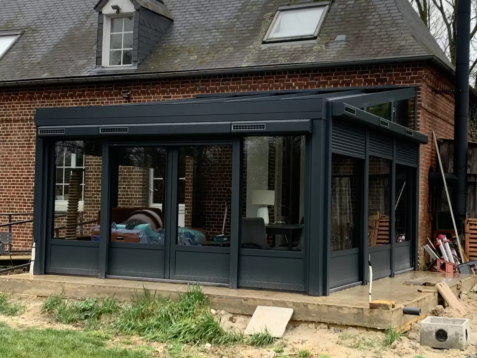 Fourniture et pose d’une véranda aluminium gris anthracite avec volets roulants solaires sur le secteur de Dieppe Fourniture et pose d’une véranda aluminium gris anthracite avec volets roulants solaires sur le secteur de Dieppe