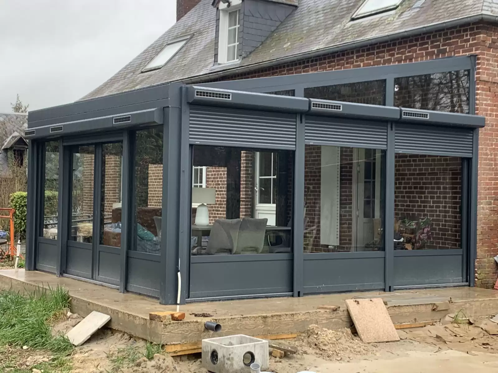 Fourniture et pose d’une véranda aluminium gris anthracite avec volets roulants solaires sur le secteur de Dieppe Fourniture et pose d’une véranda aluminium gris anthracite avec volets roulants solaires sur le secteur de Dieppe